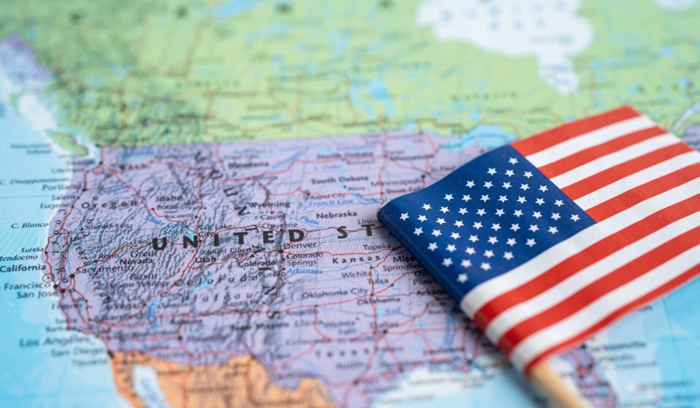 National flag of America (USA) placed on top of map showing the USA